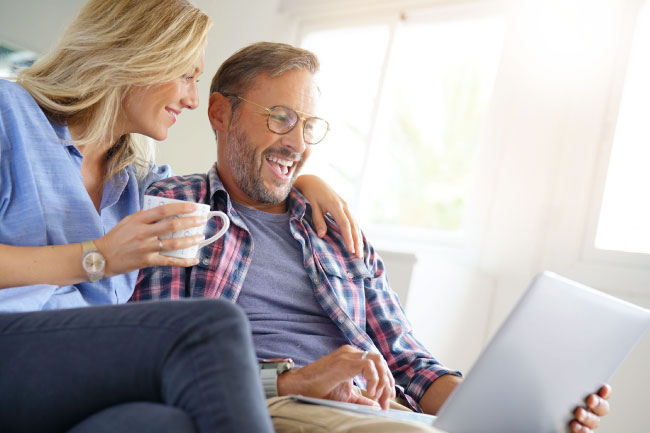 Happy couple on laptop topping up their ISAs with MyPlans