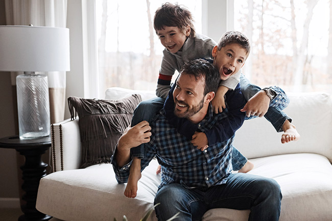 Father and daughter sitting on a grey sofa using an iPad to activate their online Child Trust Fund account