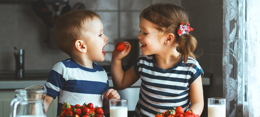 Siblings eating strawberries who have Stocks and Shares and Cash Junior ISAs