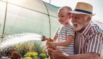 Grandparent watering plants with grandson who has a Foresters Junior ISA