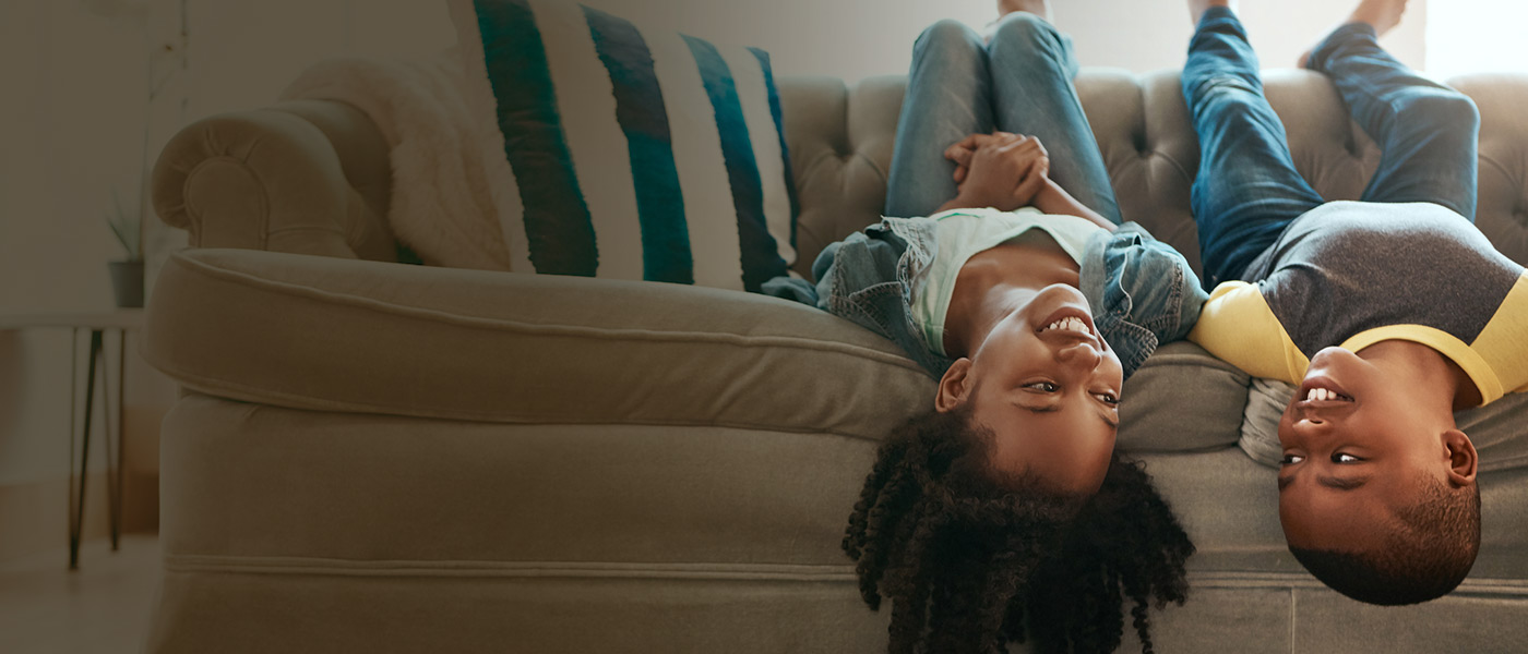 Brother and sister on sofa with a Forester Life children's savings account