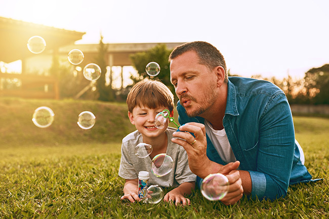 Happy dad blowing bubbles with child after opening a Junior ISA with Foresters