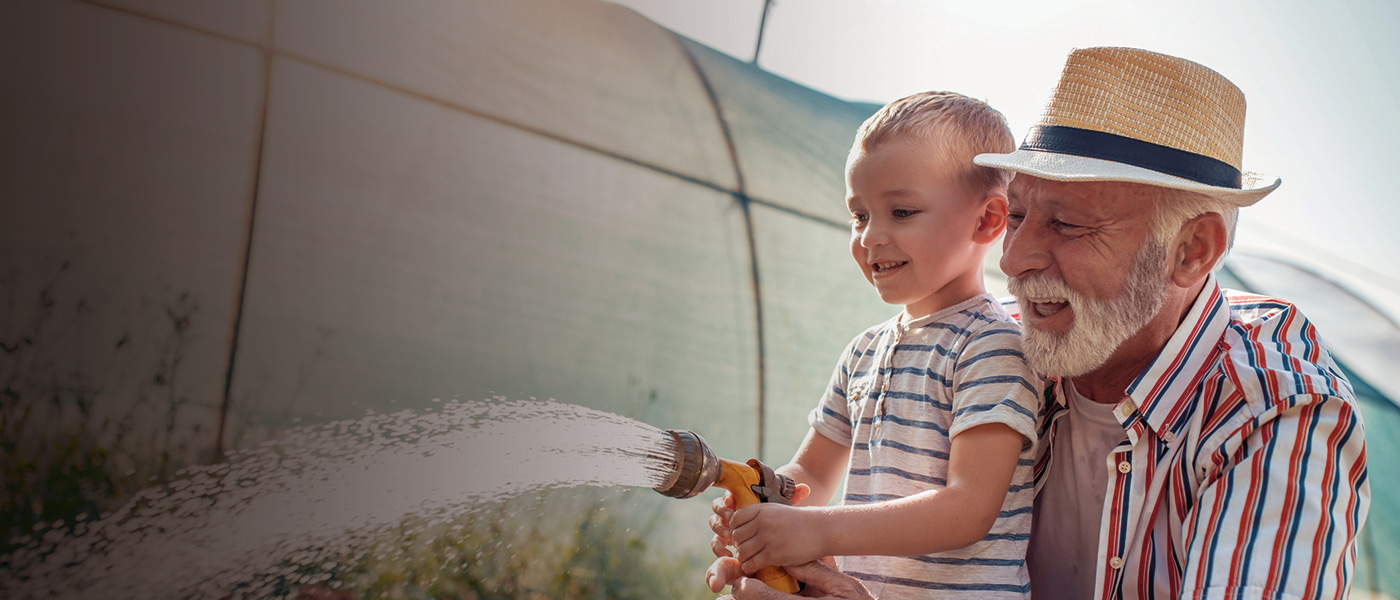 A grandfather watering plants with grandson who he's been saving for
