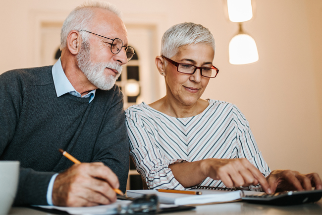 Older couple sitting at the dining table working out Plan value