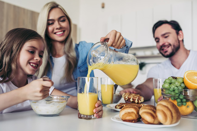 Happy family discussing daughter's Junior ISA Plan value at the breakfast table