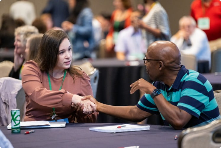 Man and woman shaking hands at meeting table